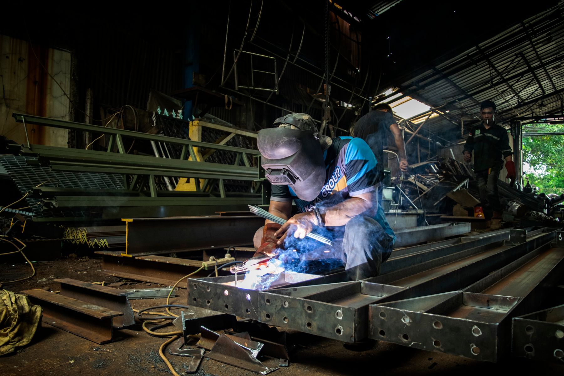 Welder at work in a dark auto workshop